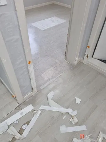 필름이 뜯겨 바닥에 떨어져 있고 문틀 하단이 파인 상태