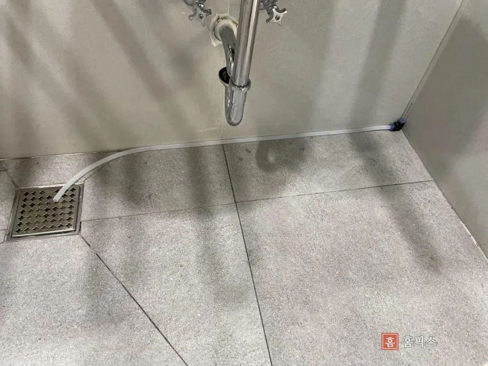 화장실 벽 모서리를 따라 배수구까지 이어진 드레인 호스 끝단