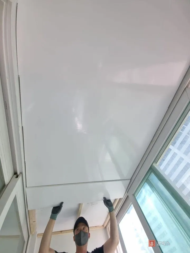 목재 골조 위에 리빙보드를 밀어 올려 붙이는 작업 장면