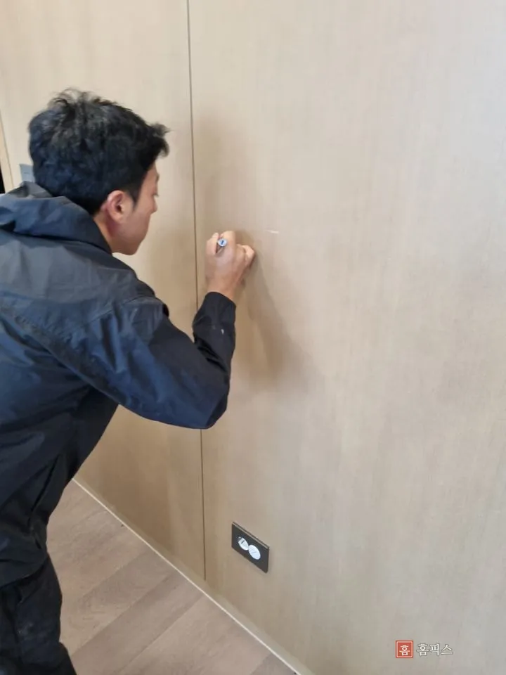 작업자가 마커로 아트월 패널에 나뭇결 무늬를 그리는 모습