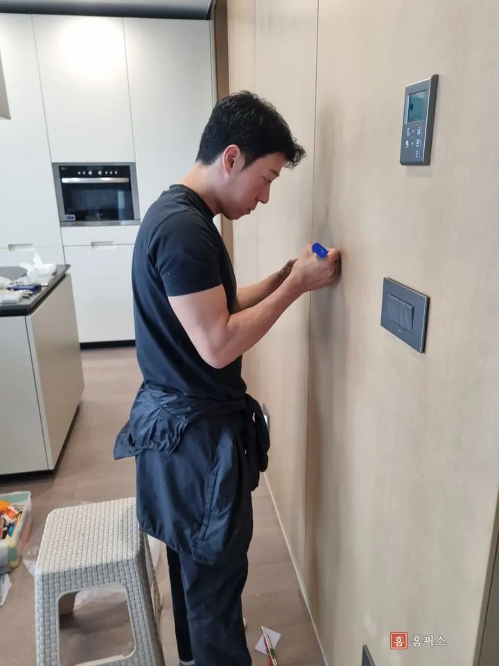 주방 옆 벽면에서 복원제를 스크래치 부위에 채우는 작업 모습