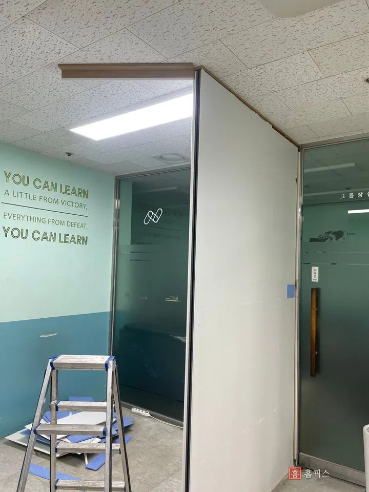 석고보드를 일부 걷어내고 골조와 유리 파티션이 드러난 상태